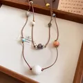 Détail d'un collier à double cordon en cuir orné de diverses perles en bois colorées. - Marron-Double Couche