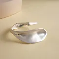 Nahaufnahme eines minimalistischen, mattsilbernen, blattförmigen Armreif-Armbands - Silber Matt