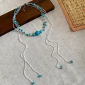 Close-up view of bohemian turquoise stone beaded multi-layer fringe necklace on linen - Blue