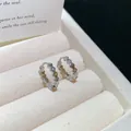 Close-up of 18k gold plated hoop earrings with clear zircon stones in a box. - Clasp Back / Silver