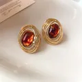 Nahaufnahme von ovalen Vintage-Ohrringen aus Harz mit hohlem, goldfarbenem Metall - Braun