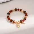 Close-up of retro tiger eye and glass beaded bracelet with a crystal gourd pendant. - Gold, Brown, Red, Gourd