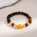 Macro detail of vintage tiger eye stone and glass beaded bracelet on a textured stone surface - Coffee-Yellow-Round