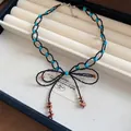 Dettaglio di una collana a fiocco con perline nere, accenti turchesi e nappe in pietra. - Girocollo Artigianale Con Perline Fiocco E Nappina (HN13743) / Patchwork Nero Blu Marrone