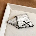 Detailed view of an elegant white polka dot hair claw clip with black lace edges - White