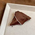 Detailed view of elegant brown polka dot hair claw clip with white lace trim and bow - Brown