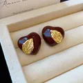Retro burgunderrote Emaille-Herzohrstecker mit goldenem Blattakzent auf Schmuckdisplay - Herz Blatt Stil / Rot