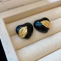 Detailaufnahme von schwarzen herzförmigen Vintage-Ohrringen mit Goldblatt in Box - Herz Blatt Stil / Schwarz
