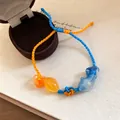 Detailweergave van een geweven koi-vis armband met oranje en blauw verstelbaar koord. - Blauw-Oranje