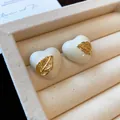 Detail von 18k vergoldeten Herzohrringen mit weißer Emaille und goldenem Blatt. - Herz Blatt Stil / Weiß