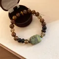 Detailopname van een houten kralenarmband in nieuwe Chinese stijl met groene jade steen - Bruin-Groen