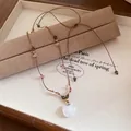 Gros plan d'un collier rétro style Maillard avec pendentif chat blanc et cordon en cuir. - Café-Blanc