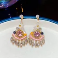 Close-up of Bohemian crystal pendant earrings with pink stones and floral accents - Pink Gold