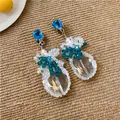 Dettaglio di orecchini pendenti vintage con zircone blu e gocce sfaccettate trasparenti - Blu