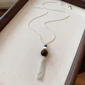 Dettaglio di un'elegante collana con nappa, perla di vetro marrone e catena in argento - Collana-Argento-Marrone-Look Pietra