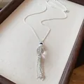 Dettaglio di una collana d'argento con nappe e perla in vetro su tessuto beige. - Collana-Argento-Bianco-Vetro