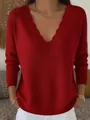Close-up detail of a red knit sweater showing the stylish scalloped V-neckline design. - Red