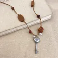 Nahaufnahme des Vintage Herz-Schlüssel-Anhängers an der ethnischen Holzperlenkette. - Holz Oval Quadrat Stil / Silber Braun