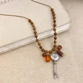 Nahaufnahme eines Vintage-Herz-Schlüsselanhängers mit Holzperlen an einer Ethno-Kette - Acryl-Runder-Stil / Silber Braun