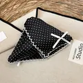 Close-up of a black polka dot fabric hair claw clip with a delicate white ribbon bow. - Black