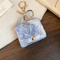 Gedetailleerd beeld van een mini denim tassenhanger met goudfolie en sluiting. - Blauw