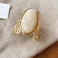 Detailed macro view of retro hollow metal armring featuring a large oval cream stone - Creamy White Marble Style / Gold