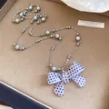 Primo piano del ciondolo a fiocco in acrilico a pois su catena di perle argentate. - Taglia L / Bianco