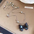 Dettaglio di una collana con fiocco a pois neri e bianchi e perle grigie su vassoio beige - Taglia S / Nero