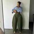 Close-up view of the olive green oversized wide-leg trousers styled with a striped shirt. - Army Green