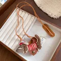 Close-up of handmade flocked dog necklace with leather cord and glasses clip detail. - Necklace-Dark Brown-Red