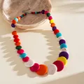 Detailed view of a vibrant multi-color graduated acrylic bead necklace on a beige stone plate - Style 42 (Multi-color)