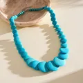 Detail view of turquoise marbled acrylic beaded necklace on textured beige background - Style 5 (Blue)