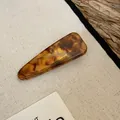 Gedetailleerd macrozicht op een vintage schildpad haarklem van acryl in amberkleur - Eendenbekclip-Stijl 3