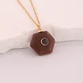 Macro detail of a hexagonal brown goldstone pendant with blue inlay on gold chain - Coffee