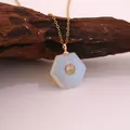 Detail of a hexagonal opal stone pendant on a gold plated stainless steel chain necklace. - Opal
