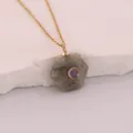Detailed macro shot of hexagonal natural stone pendant with purple zircon inlay - Grey Stone