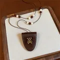 Close-up of brown leather bear pendant necklace with white polka dots and beaded string. - Teddy Bear / Coffee