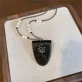 Detailed view of a stylish black cat pendant necklace with pearls and polka dot patterns. - Cat / Black