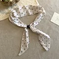 Primer plano de un pañuelo retro de lunares en algodón y lino con broche de perla negra - Collar-Beige-Lunares