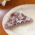 Close-up detail of retro acrylic bow hair claw clip featuring orange checkered pattern design - Coffee Stripe Claw Clip