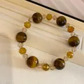 Elegante pulsera de cristal con ojo de tigre y cuentas de ámbar en una bandeja beige. - Pulsera-Marrón