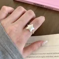 Detailed view of a minimalist matte silver star-shaped open ring worn on a finger - Silver Matte Star Open Ring (JZ5487) / Open Adjustable