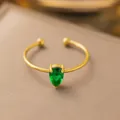 Vista macro di un anello aperto in acciaio dorato con gemma verde a forma di pera - Stile Goccia d'Acqua Strass Verde (F187) / Oro