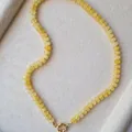 Detailopname van een gele natuursteen abacus kralenketting met goudkleurige veersluiting - 43cm / Gele Steen met Gouden Kralen