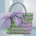 Detail view of colorful woven tote bag featuring a large purple fabric bow decoration. - Small (With Purple Bow) / Green Purple
