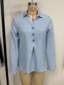 Close-up detail of a light blue long-sleeved shirt featuring wooden buttons and front pleats - S / Tops / Light Blue