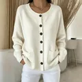 Detail view of a cream round neck knitted cardigan with dark buttons and front pockets - S / Tops / Off White
