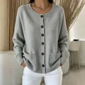 Detail shot of a soft grey knit cardigan featuring brown buttons and practical front pockets. - S / Tops / Gray
