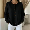 Detail view of a women's black crewneck knitted cardigan with brown buttons - Black