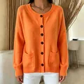 Close-up of a vibrant orange round neck knitted cardigan with front pockets and buttons - S / Tops / Orange